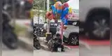 Niño le enseña a leer a su hermano menor mientras vende globos en la calle en Indonesia