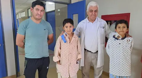 Menor André con bata naranja junto a médico que lo atendió.