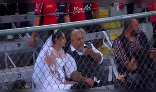 Recién casados asisten a un partido de futbol vestidos con sus trajes de matrimonio. elpopular.pe