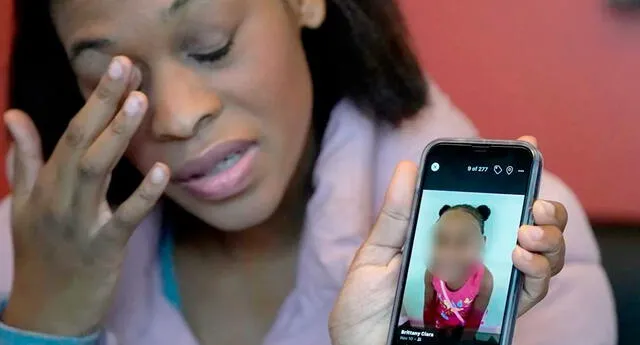 Brittany Tichenor-Cox sostiene la foto de su hija en su celular durante una entrevista al medio AP.