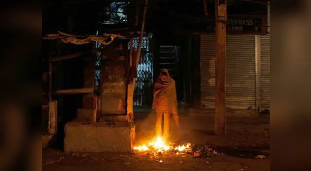 Un mendigo espera que el fuego le caliente el cuerpo en Nochebuena. No tiene una taza en donde tomar agua.