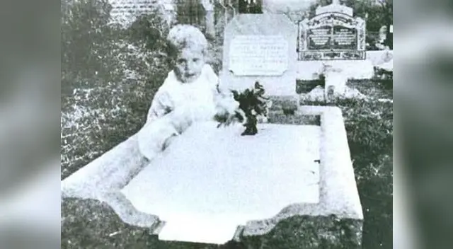 Niño desconocido sentado en una tumba.