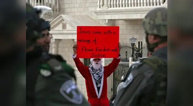 El mundo vide la Navidad desde distintos puntos de vista (manifestante vestido de Papá Noel protesta en enfrentamiento en Belén, Palestina)