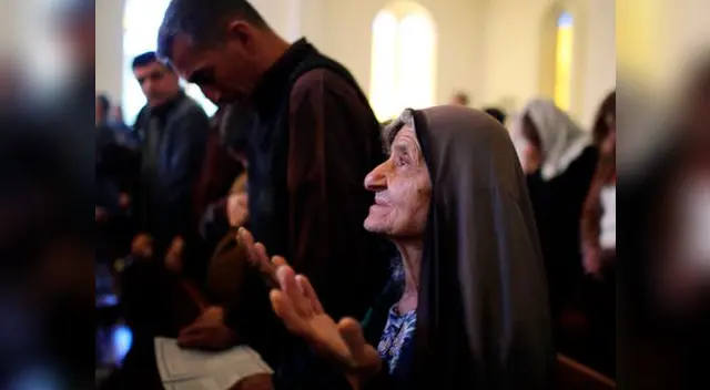 El mundo vive la Navidad desde distintos puntos de vista (mujer reza en iglesia de Baghdad).