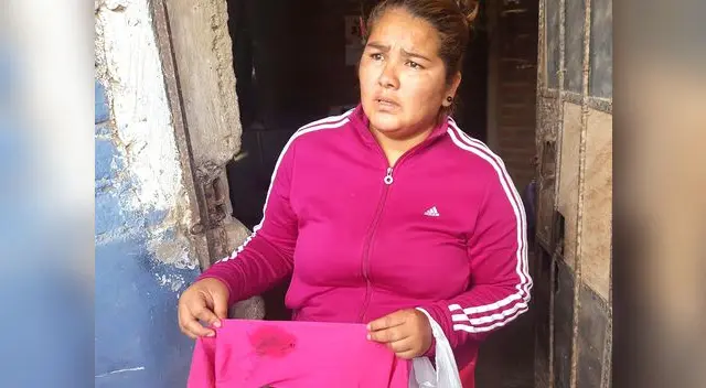 La mamá mostrando la ropa de su hijita herida.