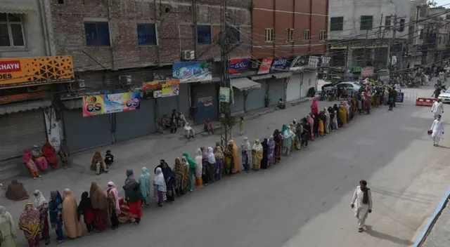 La mujeres hacen cola para recaudar dinero en efectivo de asistencia financiera gubernamental sin respetar el distanciamiento social. La mujeres hacen cola para recaudar dinero en efectivo de asistencia financiera gubernamental sin respetar el distanciamiento social.