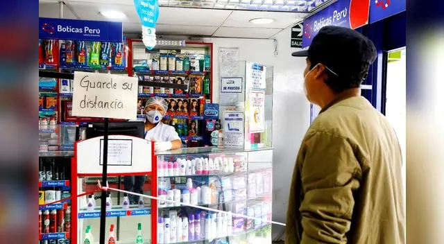 Las cajeras de las farmacias usan un vidrio para atender al cliente y usan un pedazo de cartón para recibir el dinero por el medicamento.