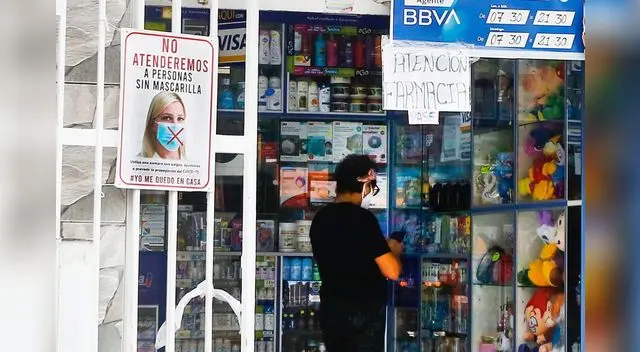 Las cajeras de las farmacias usan un vidrio para atender al cliente y colocan un pedazo de cartón para recibir el dinero por el medicamento.