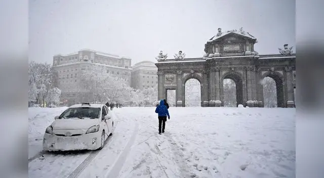 La gente pasa por la Puerta de Alcalá en medio de una fuerte nevada en Madrid el 9 de enero de 2021.