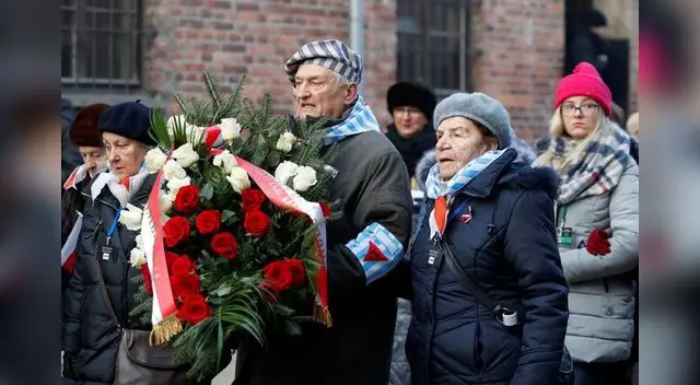 Sobrevivientes del Holocausto llegan al llamado "muro de la muerte" del campo de concentración nazi de Auschwitz.