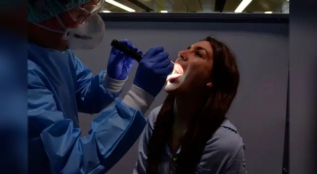 Un especialista del aeropuerto de Viena recoge una muestra de saliva de una pasajera.