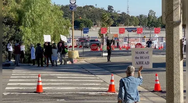 Manifestantes sostienen pancartas cerca de la entrada del centro de vacunación en el estadio de los Dodgers en Los Ángeles, EE.UU., 30 de enero de 2021.