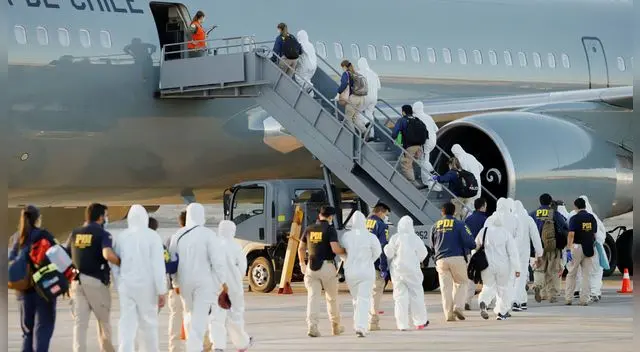 Agentes de policía escoltan a los migrantes mientras son deportados en la ciudad norteña de Iquique, Chile, 10 de febrero de 2021.