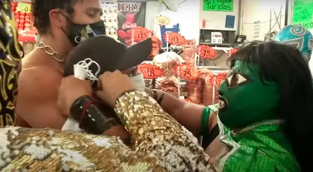 Los luchadores colocando una mascarilla a uno de los transeúntes. Los luchadores colocando una mascarilla a uno de los transeúntes.