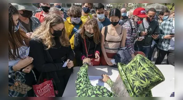 Un hombre con prendas con figuras de cannabis reparte cigarrillos de marihuana en Nueva York durante el evento "Joints for Jabs".