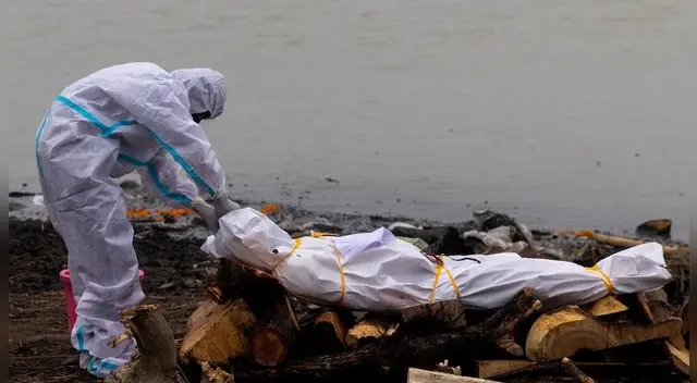 Un hombre junto al cadáver de un fallecido por COVID-19 antes de su cremación a orillas del río Ganges, en Garhmukteshwar (Uttar Pradesh, la India), el 6 de mayo de 2021. Un hombre junto al cadáver de un fallecido por COVID-19 antes de su cremación a orillas del río Ganges, en Garhmukteshwar (Uttar Pradesh, la India), el 6 de mayo de 2021.