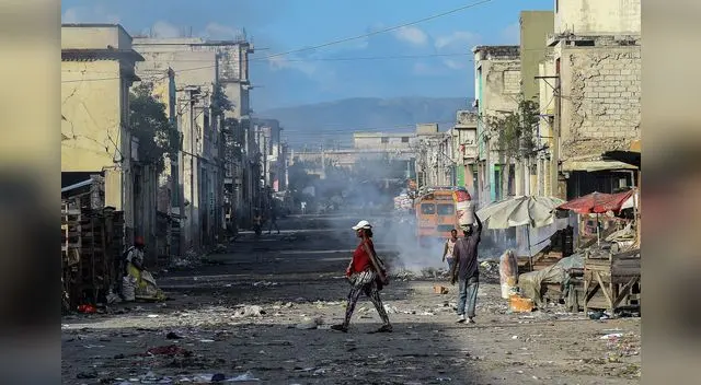 Residentes de un suburbio de Haití caminan por sus calles poco después de un tiroteo entre bandas criminales el 20 de diciembre de 2019.