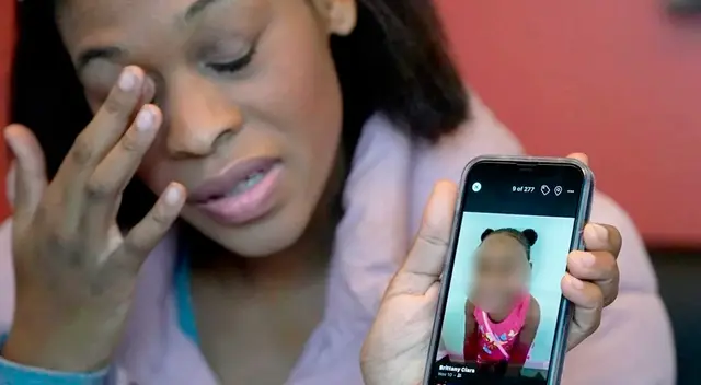 Brittany Tichenor-Cox sostiene la foto de su hija en su celular durante una entrevista al medio AP.