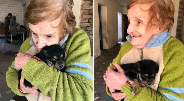En la imagen se ve como la tierna adulta mayor sonríe mientras abraza al pequeño perrito negro.