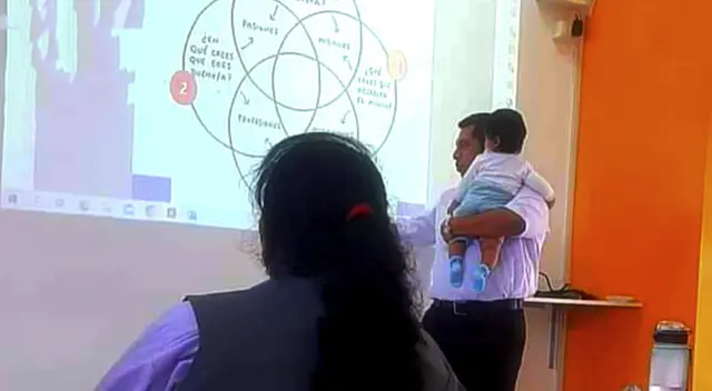 Profesor de Huaral ayuda a alumna en clase y carga a su bebé para que termine trabajo en clase.