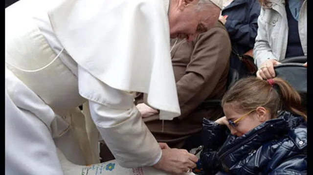 El Papa Francisco firma el yeso de una niña.