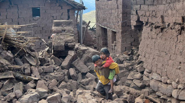 Niños caminan en medio de casas derrumbadas. 