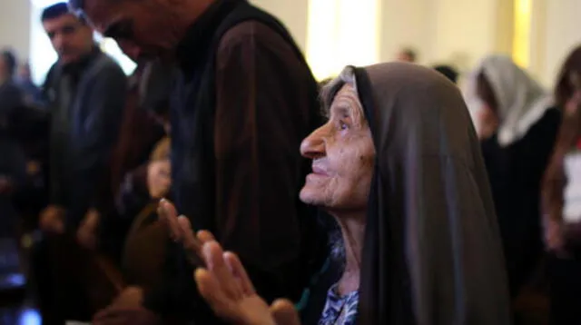 El mundo vive la Navidad desde distintos puntos de vista (mujer reza en iglesia de Baghdad).