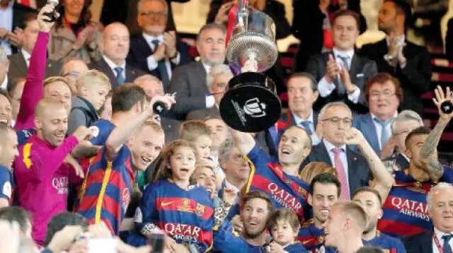 Iniesta levanta el trofeo que refleja la conquista del barcelona, mientras sus compañeros explotan de alegría juto con la hinchada