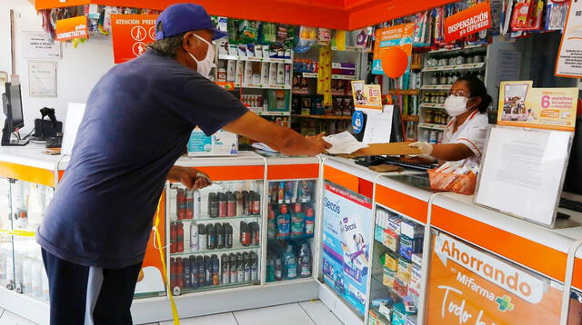 Las cajeras de las farmacias usan un vidrio para atender al cliente y colocan un pedazo de cartón para recibir el dinero por el medicamento.