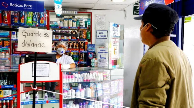 Las cajeras de las farmacias usan un vidrio para atender al cliente y usan un pedazo de cartón para recibir el dinero por el medicamento.