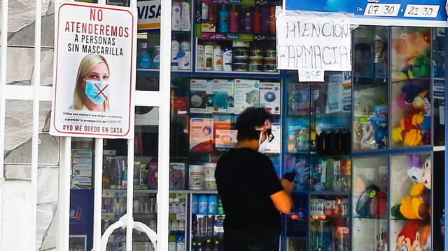 Las cajeras de las farmacias usan un vidrio para atender al cliente y colocan un pedazo de cartón para recibir el dinero por el medicamento.