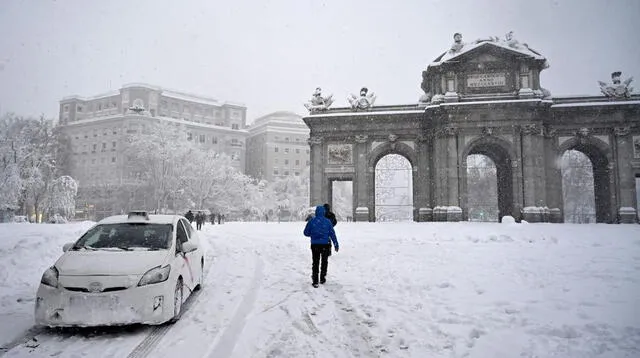 La gente pasa por la Puerta de Alcalá en medio de una fuerte nevada en Madrid el 9 de enero de 2021.