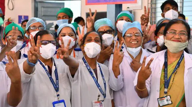 Personal sanitario del Hospital Rajawadi hace el signo de la victoria mientras esperan el inicio de la campaña de vacunación contra el coronavirus.