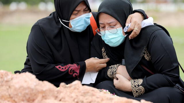 Dos mujeres lloran la muerte de un familiar en un cementerio de Batu Caves, Malasia.