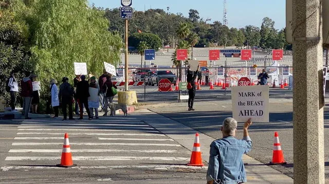 Manifestantes sostienen pancartas cerca de la entrada del centro de vacunación en el estadio de los Dodgers en Los Ángeles, EE.UU., 30 de enero de 2021.
