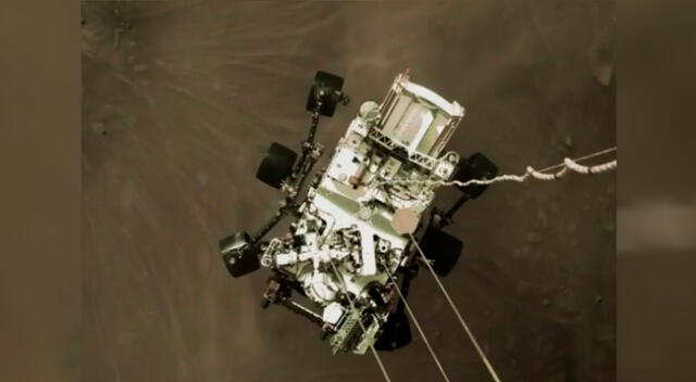 El robot Perseverance cuando estaba aterrizando en Marte, visto desde el cohete que ayudó en su descenso.