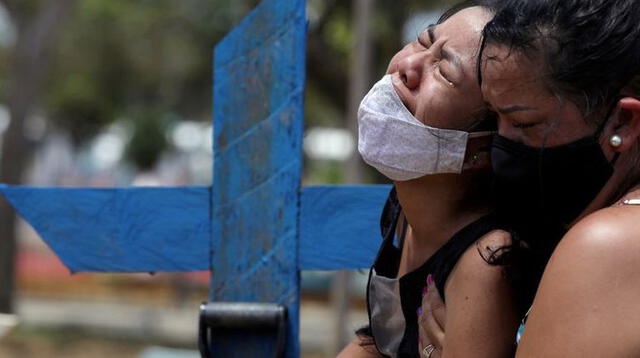 Imagen de archivo de dos personas llorando por la muerte de un familiar en el cementerio Parque Taruma de Manaos, Brasil. 17 enero 2021.