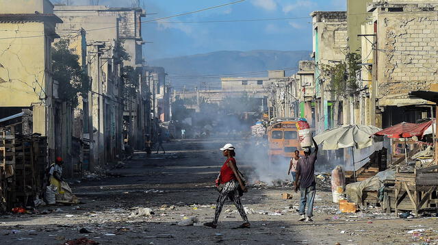 Residentes de un suburbio de Haití caminan por sus calles poco después de un tiroteo entre bandas criminales el 20 de diciembre de 2019.