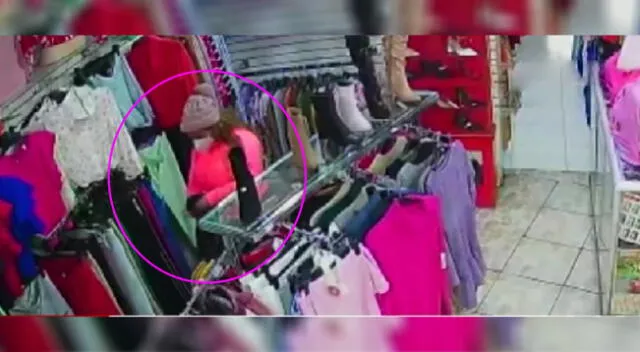 Una de las ladronas metiendo ropa que acaba de robar a una mochila para luego huir como si nada